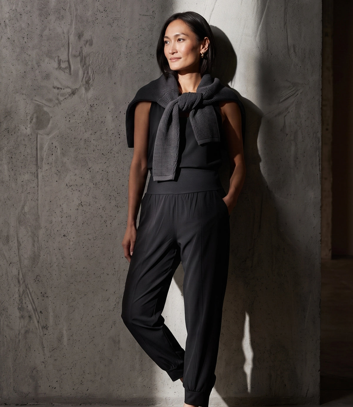 Le monde des hiboux Woven high-waisted jogger pants in black, styled with a sleeveless top and a charcoal knit sweater tied over the shoulders
