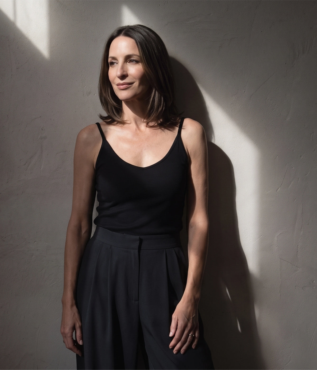Woman in a black ribbed built-in bra camisole standing in soft window light