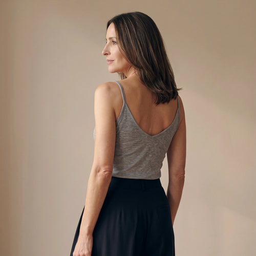 Back view of a melange grey camisole with a deep V back, worn with black tailored pants