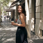 Smiling woman in a melange grey built-in bra camisole with a canvas tote bag and takeaway coffee