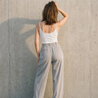 Back view of a white built-in bra camisole with a low scoop back, worn with black pants