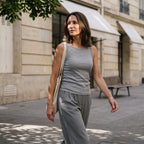 Woman walking in a melange grey built-in bra tank top and grey pleated pants with a canvas tote bag