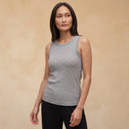 Woman in a melange grey ribbed built-in bra tank top with a gold necklace against a warm beige wall