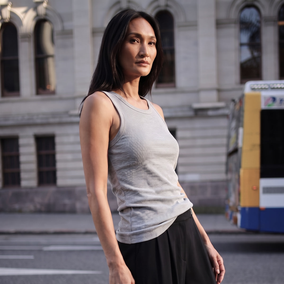 Melange grey ribbed built-in bra tank top with navy pleated pants, walking on a street