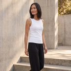 Off white ribbed built-in bra tank top with black jogger pants against a concrete wall
