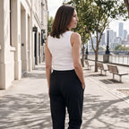 Back view of an off white tank top with black jogger pants, walking along a sunny path