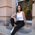 Le monde des hiboux built-in bra tank top in off white, worn with black jogger pants, seated on a step