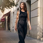 Woman walking in a black built-in bra tank top and black tailored pants with a canvas tote bag