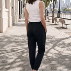 Back view of black jersey jogger pants with a wide waistband and back seam detail, one hand in pocket