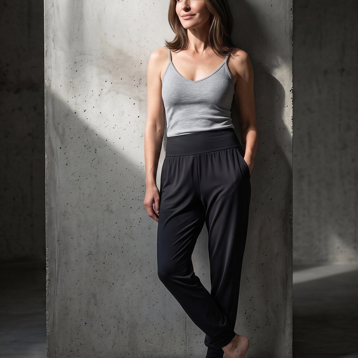 Black jersey jogger pants with a wide high waistband, grey camisole, standing in a shaft of sunlight