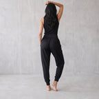 Back view of black jogger pants with a wide waistband and ankle cuffs, one arm raised