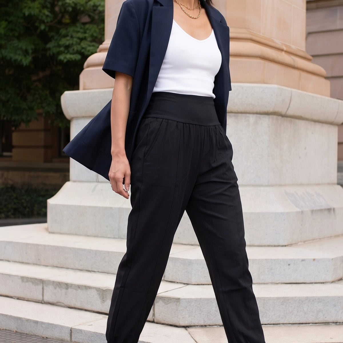 Black woven jogger pants worn with a navy short-sleeve blazer and white camisole, walking in daylight