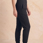 Side view of black woven jogger pants showing the waistband, side pocket and tapered leg